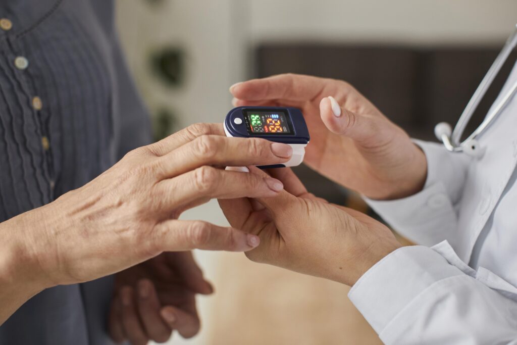 female doctor checking elder patient's oxygen level