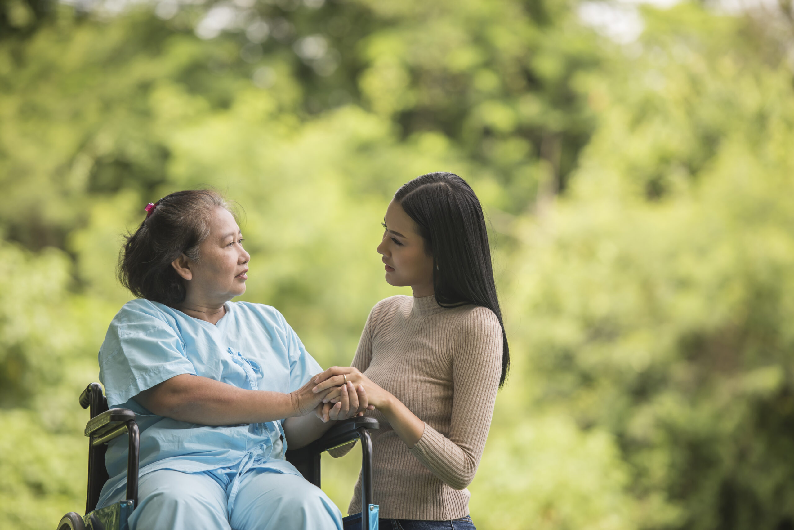 Granddaughter talking with her grandmother sitting on wheelchair, cheerful concept, happy family